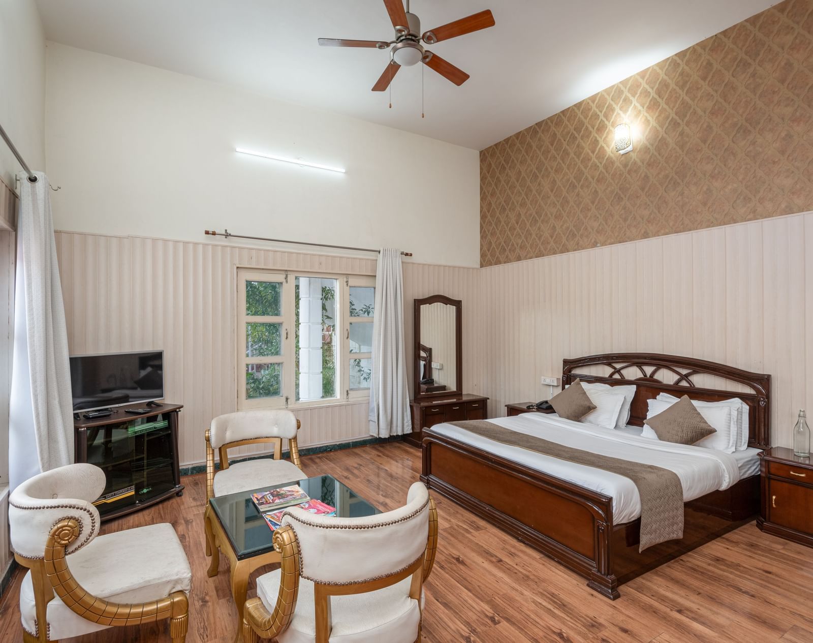 Spacious and bright guest room at DLS Tehri Club Resort with a king-size bed and a seating area.